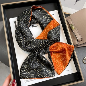 Elegant double-sided silk scarf with floral and geometric patterns on a luxury tray