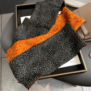 Detail of double-sided printed silk scarf with wave and floral patterns on a bag