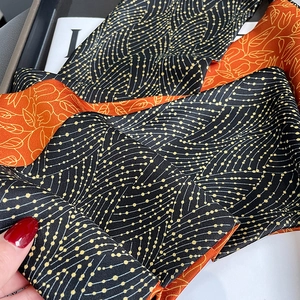 Detailed close-up of double-sided silk scarf with gold wave pattern and floral print
