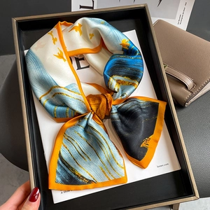 Detail of artistic silk scarf with orange borders and blue bird print on a designer bag