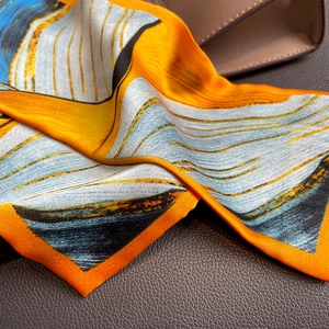 Detailed close-up showing the silk scarf's twill texture and vibrant abstract print patterns