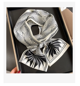 Détail d'un foulard en soie à motifs géométriques noir et blanc plié sur un plateau chic
