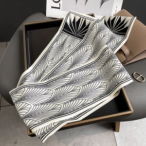 Détail d'un foulard twilly en soie géométrique noir et blanc avec motif d'éventail sur plateau