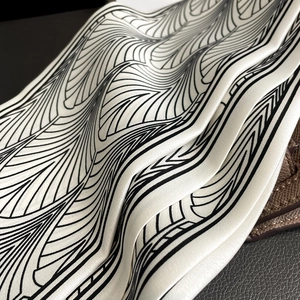 Détail d'un foulard en soie aux motifs géométriques noirs et blancs sur un sac