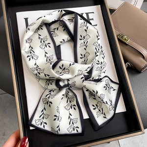 Détail d'un foulard en soie à imprimé tulipe noué en nœud sur un plateau noir