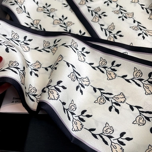 Gros plan d'un foulard en satin à motif floral avec des bordures noires élégantes