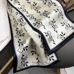 Gros plan d'un foulard étroit en soie à imprimé floral sur une surface en cuir foncé