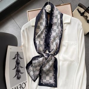 Détail d'un foulard étroit en soie avec motif pied-de-poule et lettrage sur chemise