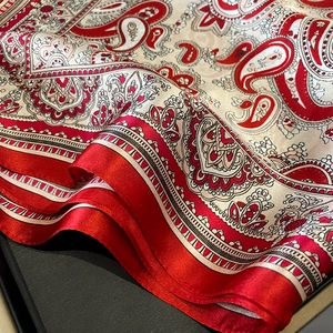Detail of red paisley silk scarf with satin edges and elegant bohemian pattern texture