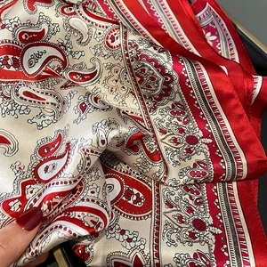 Detailed close-up of red and white paisley silk scarf with smooth satin texture and shine