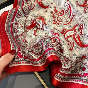Elegant red and cream silk scarf featuring a detailed paisley pattern and satin border