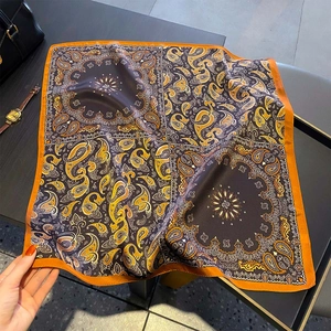 Vintage paisley print silk square scarf in warm brown and orange displayed on table