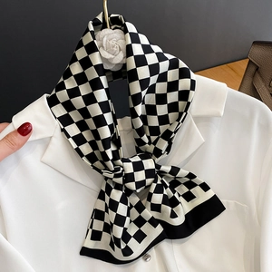 Écharpe étroite en soie à damier noir et blanc nouée sur un col de chemise blanche chic
