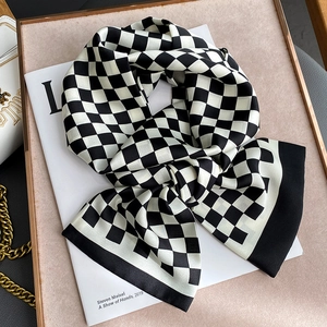 Gros plan d'un foulard en soie à carreaux noirs et blancs avec finition satinée
