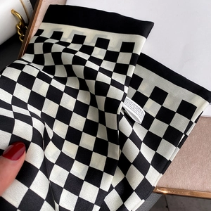 Vue détaillée d'une écharpe à damier noir et blanc en tissu polyester doux et soyeux