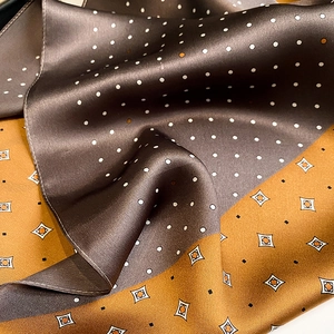 Detail of silk scarf showing brown polka dots and yellow geometric silk fabric texture