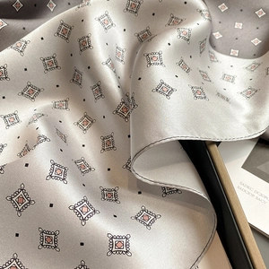 Detailed view of silver silk scarf showing geometric dot patterns and hand-rolled edges