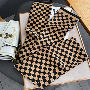 Détail d'un foulard étroit en soie à damier noué sur un sac à main comme accessoire chic