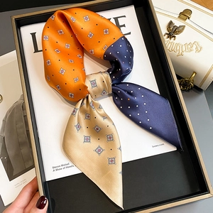 Macro detail of silk scarf with orange and navy color block and polka dot pattern