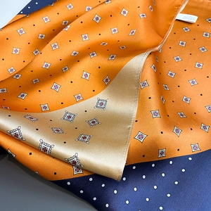 Detail of silk scarf showing orange and navy dot patterns with stitched care label