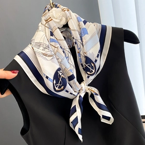 Elegant silk neck scarf with nautical anchor pattern and blue borders on a white dress