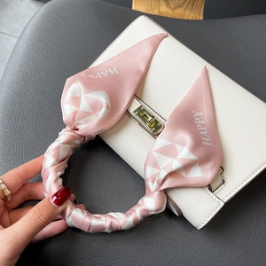 Pink and white geometric checkered silk scarf tied on a white leather handbag handle