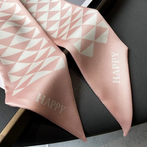 Close-up of pink satin silk scarf with geometric diamond patterns and HAPPY lettering