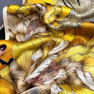 Detailed macro view of luxurious golden silk square scarf with floral print and satin luster