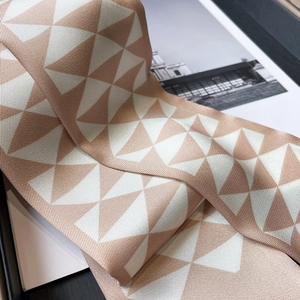 Close-up of geometric silk twill scarf with rose gold triangles and fine texture
