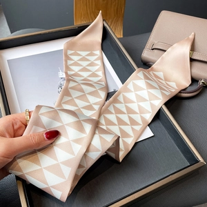 Detailed view of geometric triangle satin scarf used as a stylish handbag accessory