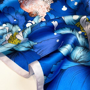 Detailed macro view of royal blue floral silk scarf with vibrant orange fish print