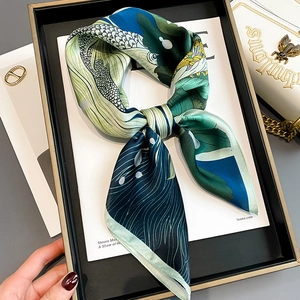 Detail of silk scarf with artistic floral patterns tied on a white leather handbag