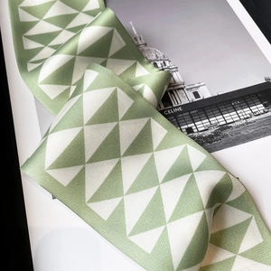Macro detail showing geometric triangle print and silk texture on green skinny scarf