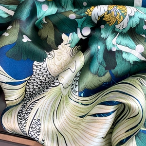 Macro detail of silk scarf showing vibrant koi fish and peony floral patterns