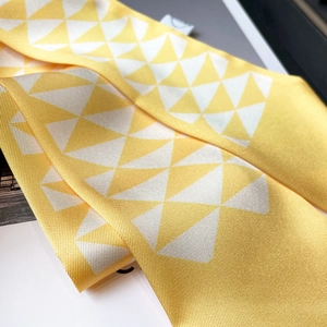 Close-up of yellow skinny silk scarf with white geometric triangle pattern and twill texture