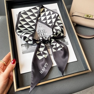 Detail of a geometric black and white silk scarf with Happy text on a tray