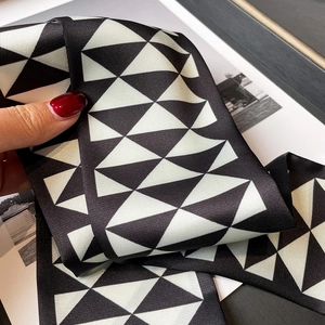 Detail of a narrow silk scarf showing monochrome geometric triangle patterns and twill texture