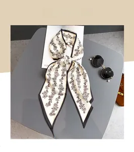 Détail d'un élégant foulard fin crème avec motifs floraux noirs sur un bureau gris