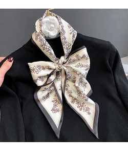 Détail d'un foulard en soie crème à fleurs noué en boucle sur un haut en tricot noir fin