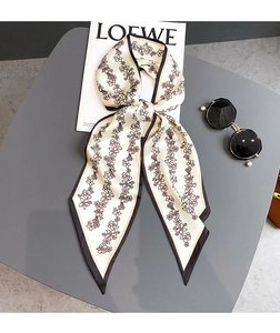 Détail d'un foulard étroit en soie à motif floral marron et bordure noire élégante