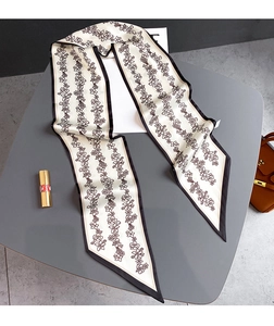 Détail d'un foulard étroit en soie à fleurs avec bordure noire sur un bureau épuré