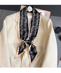 Détail d'un foulard étroit en soie à motif floral sur un blazer blanc cassé élégant