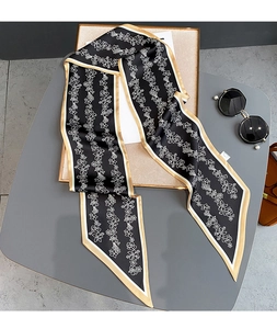 Détail d'un foulard étroit en soie avec motifs de fleurs blanches et bordure dorée chic