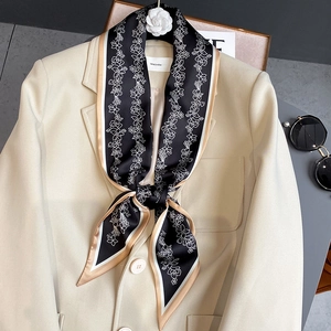 Élégant foulard étroit noir à motif floral avec bordure crème sur un blazer chic