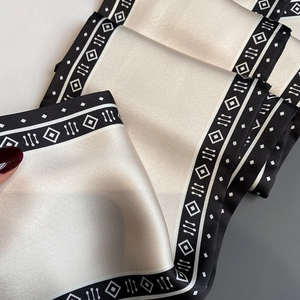Detailaufnahme eines Seidenschals mit schwarzer Bordüre und geometrischem Muster