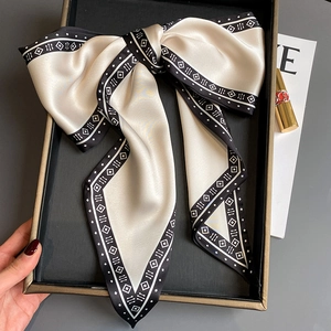 Detail eines Seidenschals mit schwarz-weißem Schleifenmuster in einer Geschenkbox