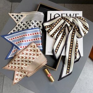 Détail de divers foulards en soie avec motifs de cœurs et pied-de-poule sur plateau