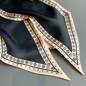 Makroaufnahme eines Seidenschals in Schwarz und Champagnergold mit geometrischem Muster