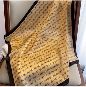 Detailed close-up of yellow silk scarf with black bow prints on a wooden chair