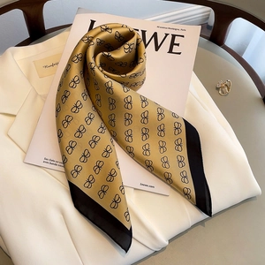 Close-up of silk scarf with black butterfly patterns on ginger yellow satin fabric